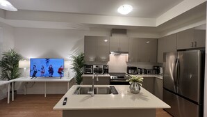 Eine moderne Küche mit Kochinsel, Edelstahlgeräten und einem Flachbildfernseher.