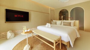 A hotel room with a bed, a bench, a small table with toiletries, a TV screen displaying 'NETFLIX', and a large mirror. - Navakiri Boutique Resort Satun (Satun)