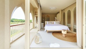 A bedroom with a large bed, a small table, and a view of greenery outside. - Navakiri Boutique Resort Satun (Satun)