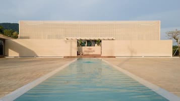 Un edificio moderno con piscina frente a él, un cartel que dice "NAVAKIRI" y fachada con diseño.