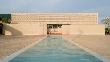 Un edificio moderno con piscina frente a él, un cartel que dice "NAVAKIRI" y fachada con diseño.