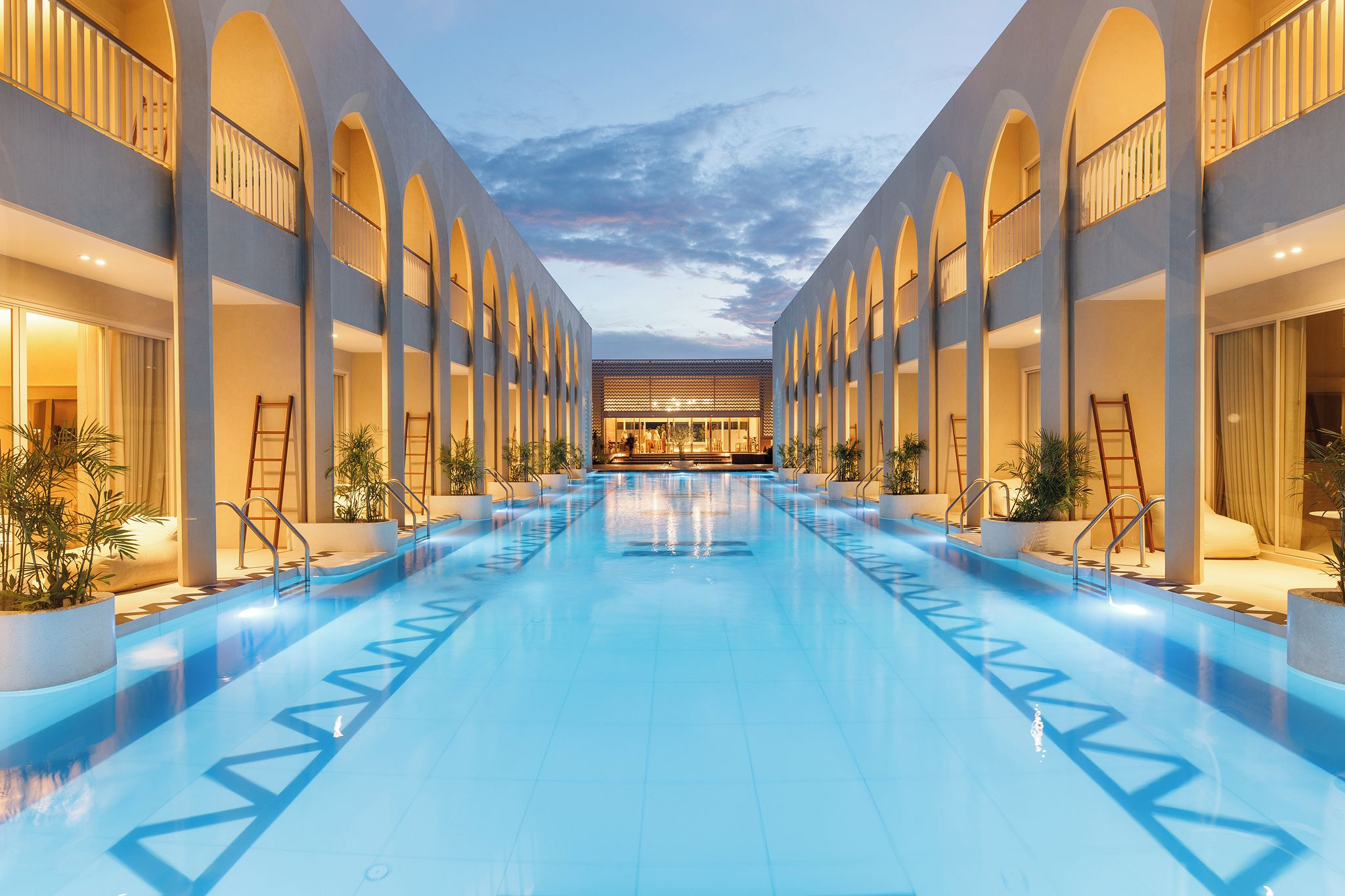 A hotel with a central swimming pool, multiple balconies, and a modern architectural design.