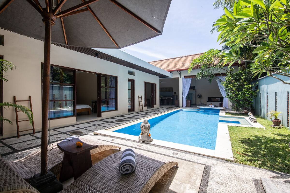 A modern house with a swimming pool, outdoor furniture, and a garden.