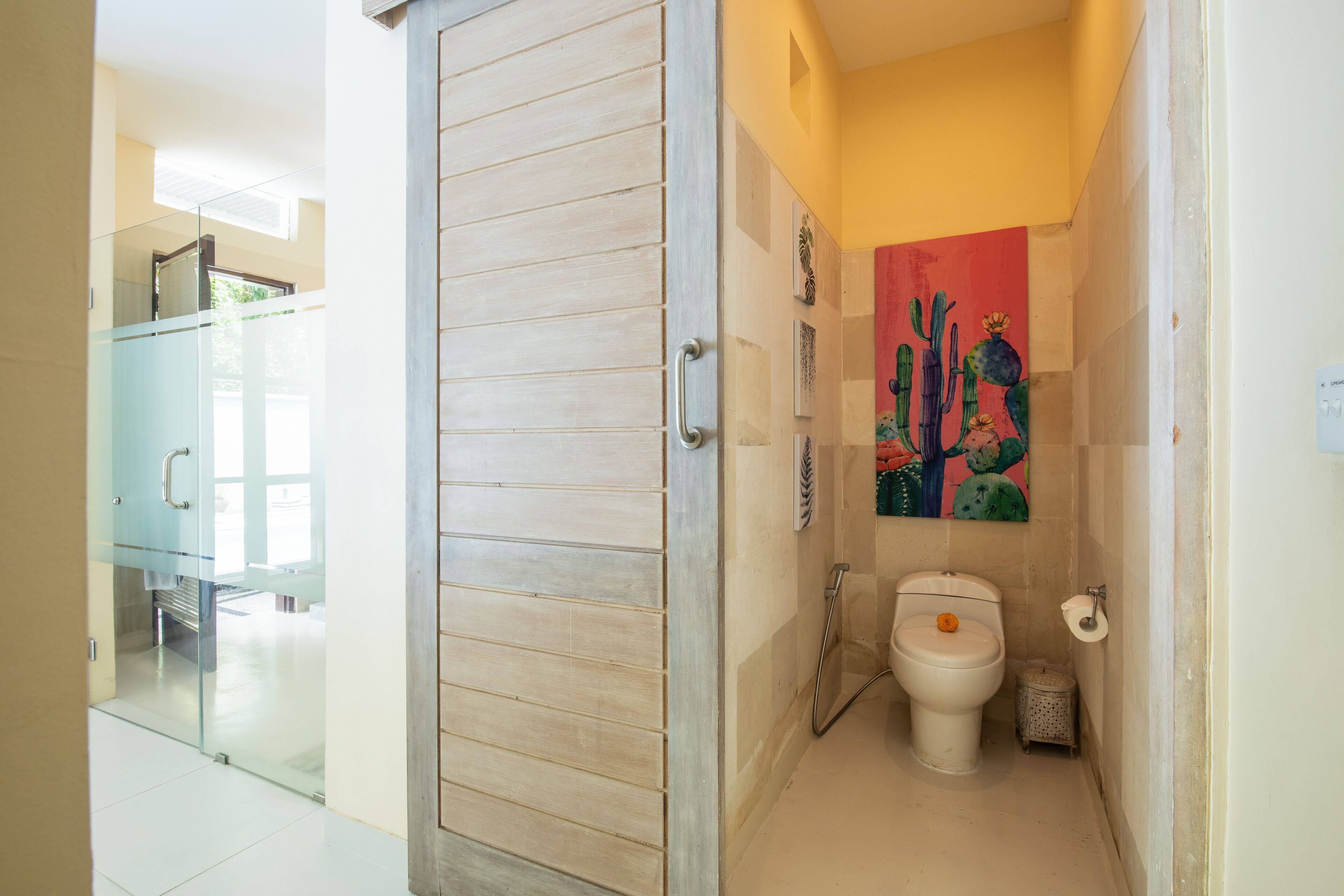 A compact bathroom with a toilet, a glass shower enclosure, and a wooden door.