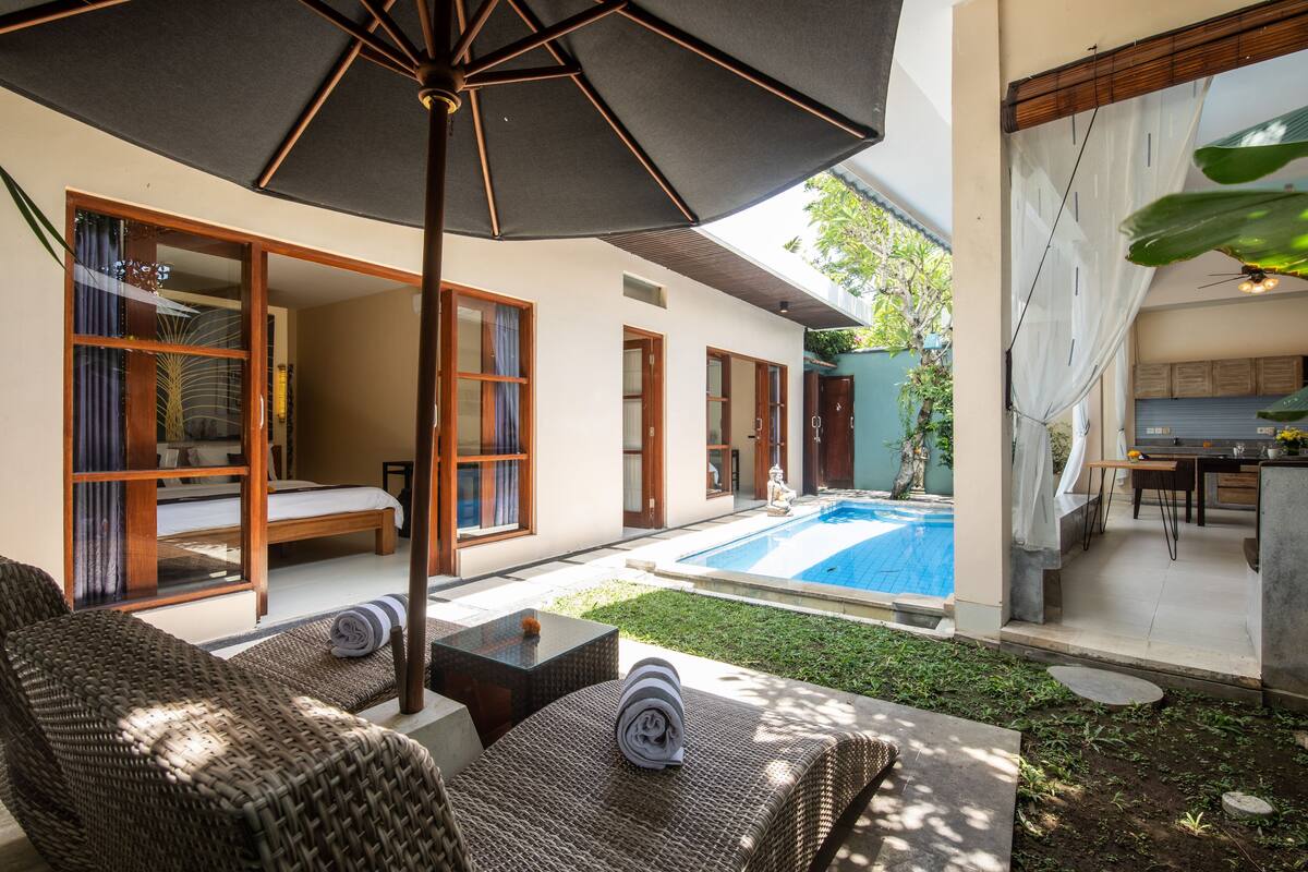 A modern outdoor living area with wicker furniture, a pool, and a covered patio.