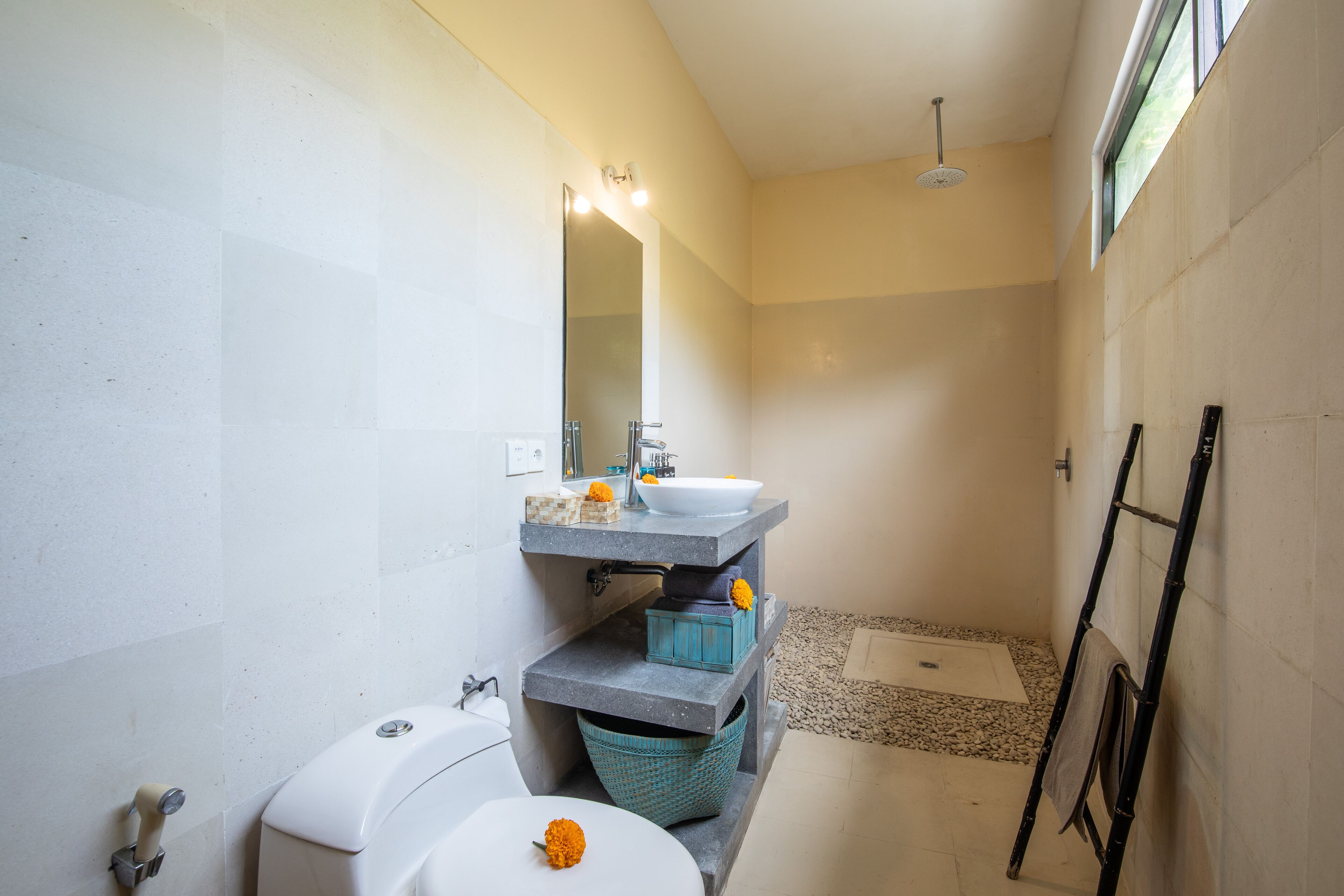 Een kleine badkamer met een wit toilet, een wastafel met spiegel erboven en een douchehoek.