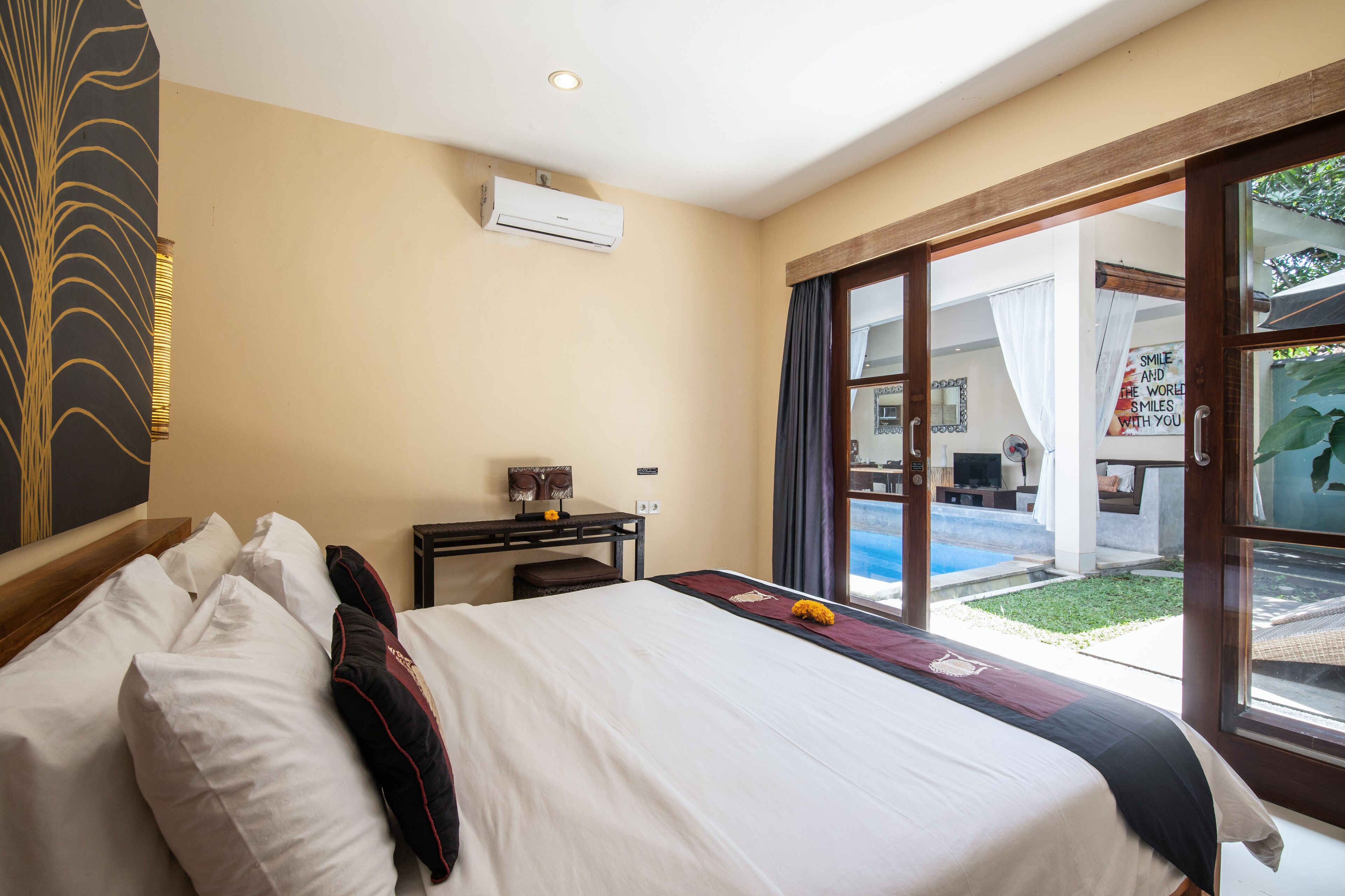 A hotel room with a bed, a desk, and a view of a swimming pool.