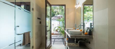 Un baño moderno con puerta de vidrio, lavamanos y espejo.