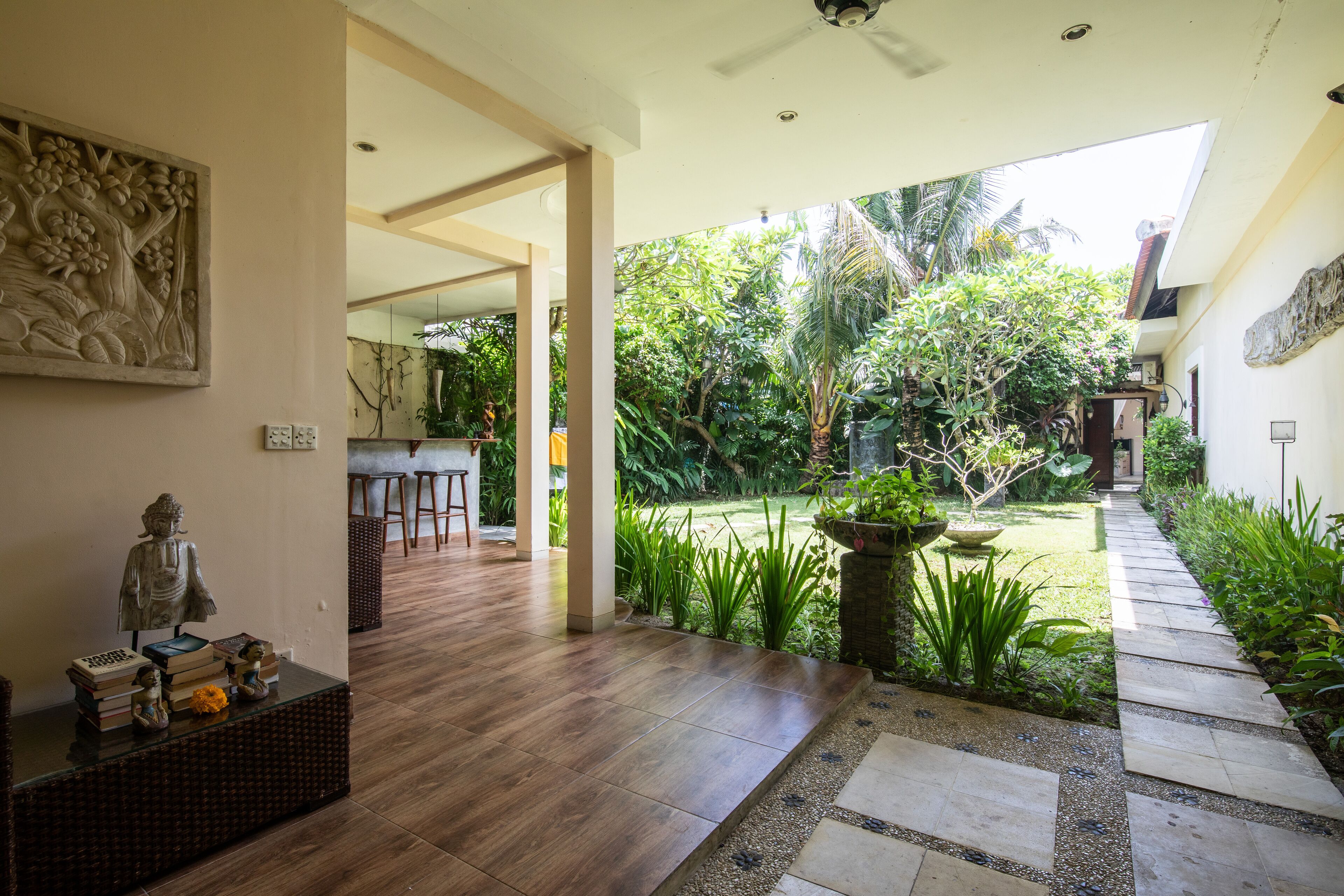 Un interior moderno con suelo de madera, una estatua y vistas a un jardín.