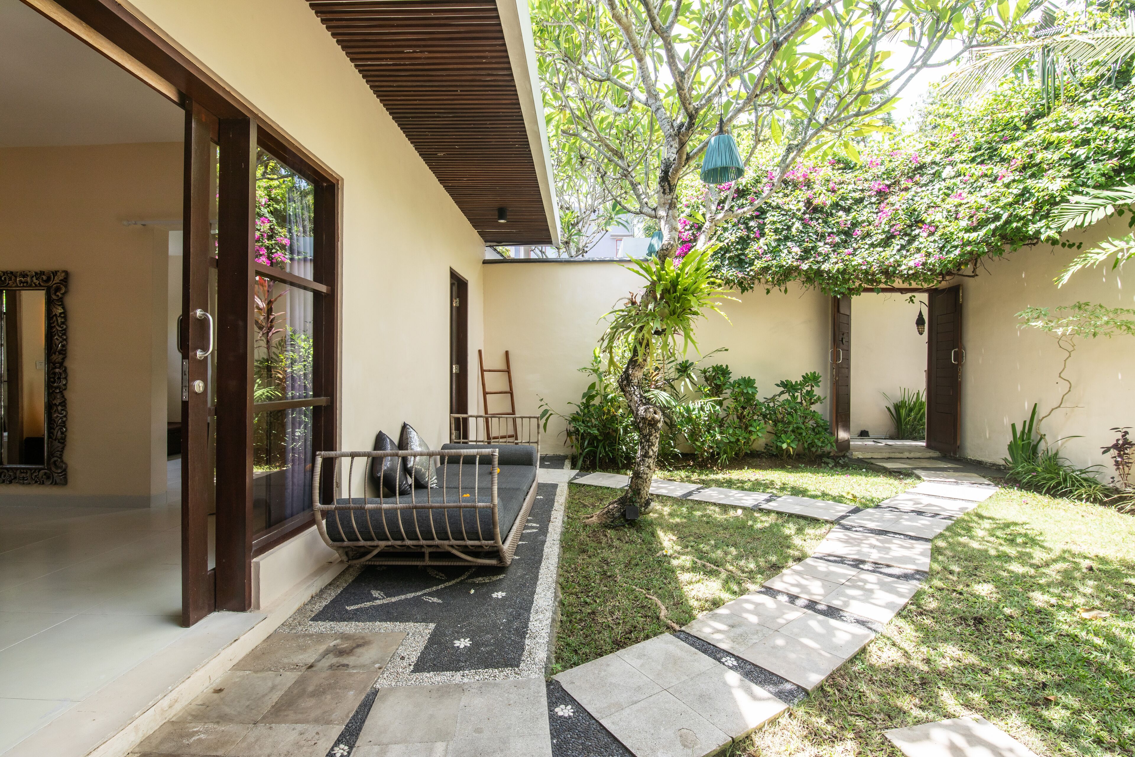 A courtyard with a sofa, a small tree, and a pathway.