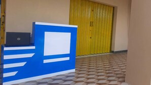 Bancada de recepção com um laptop, um design azul e branco, e uma porta amarela ao fundo.