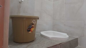 Casa de banho com sanita, um caixote do lixo e uma torneira.