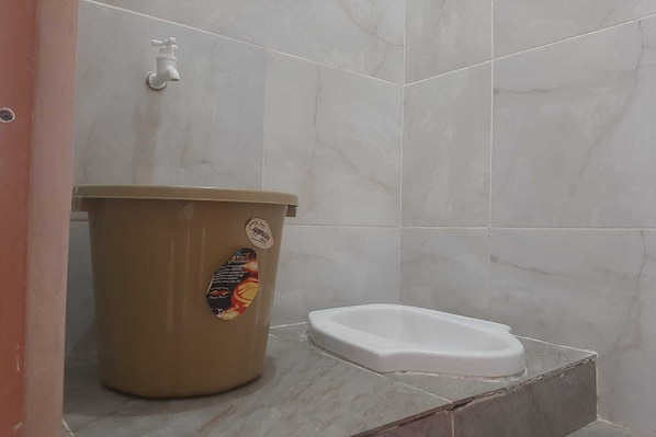 A bathroom with a toilet, a trash bin, and a faucet.