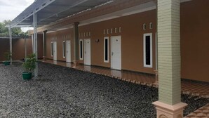 Um edifício com galeria coberta, várias portas e plantas em vasos.