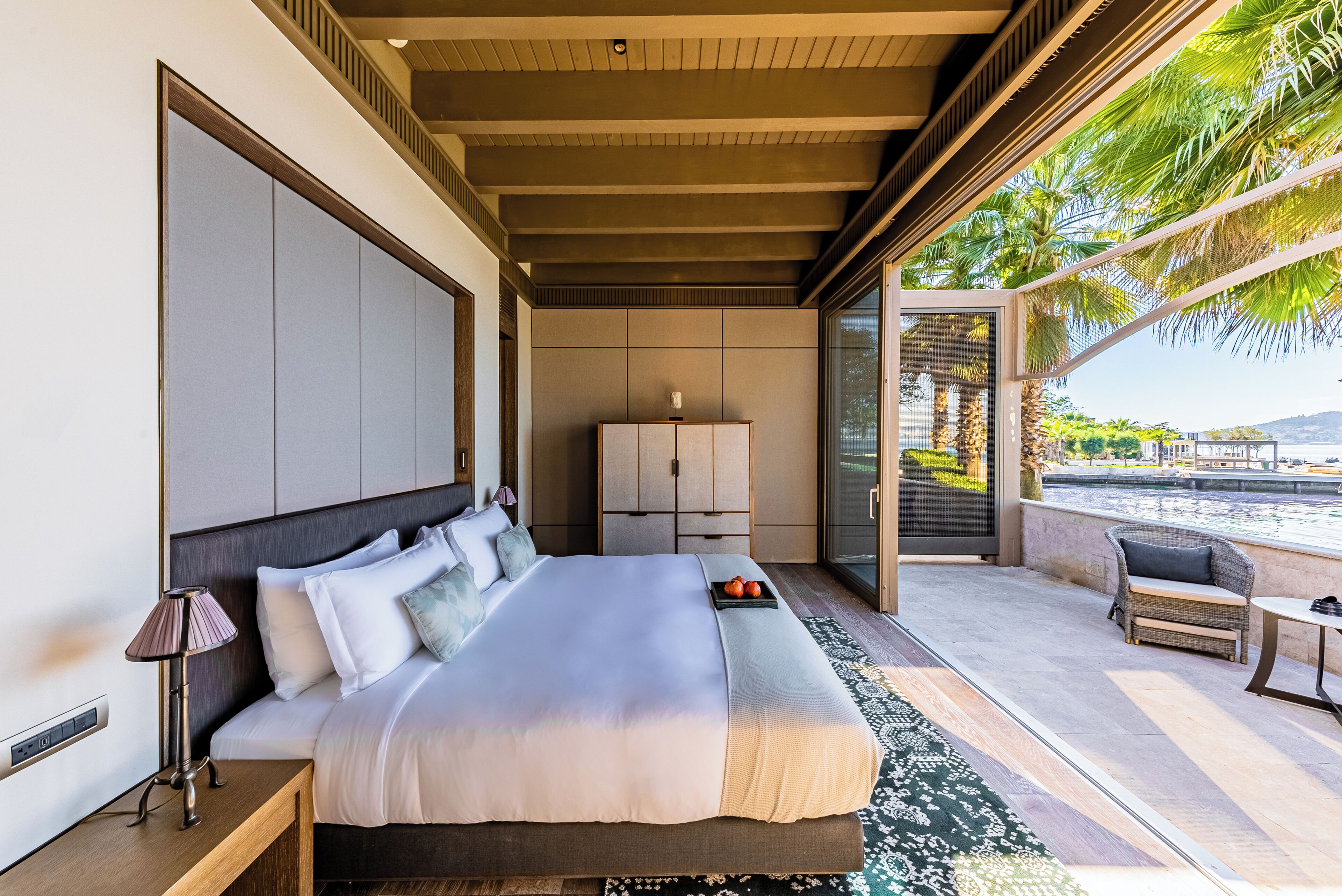 Un dormitorio moderno con una cama grande, una mesita de noche, una lámpara, un armario y vistas al exterior.