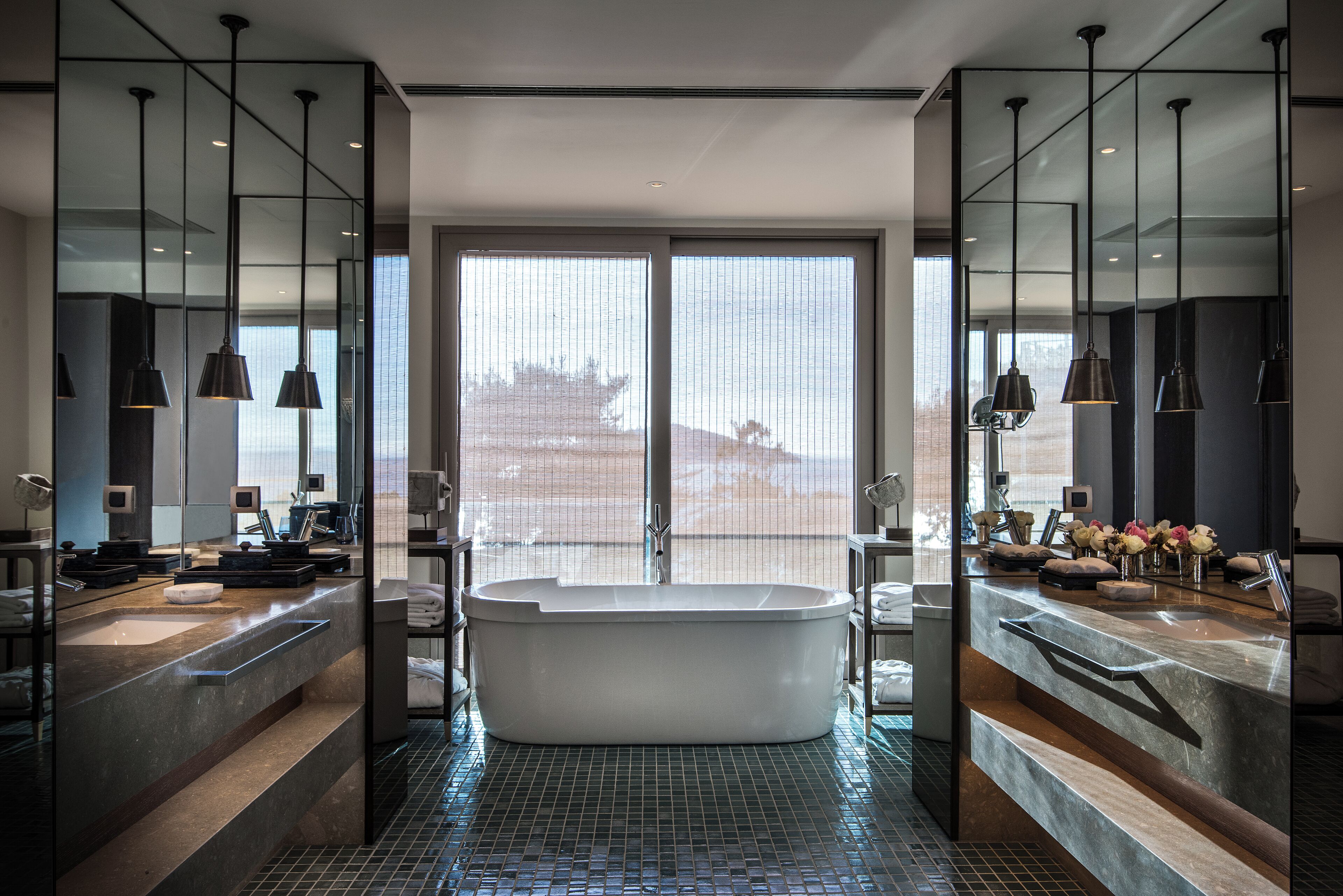 A modern bathroom with a freestanding bathtub, dual sinks, and large mirrors.