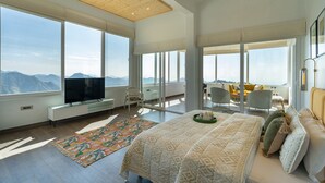 A modern bedroom with a large bed, a television, and a view of mountains through large windows. - Soul Stories - Luxury Villas and Resort, Mussorrie (Dhanaulti)