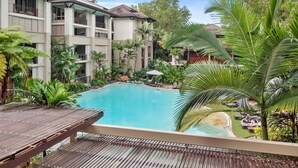 A resort with a swimming pool surrounded by lush greenery and palm trees.