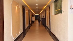 A hotel corridor with a long, narrow layout, featuring doors on both sides, a tiled floor, and overhead lighting.