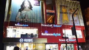 A building with a sign for 'M R Residency Lodging & Boarding' and 'Reliance Digital' store.