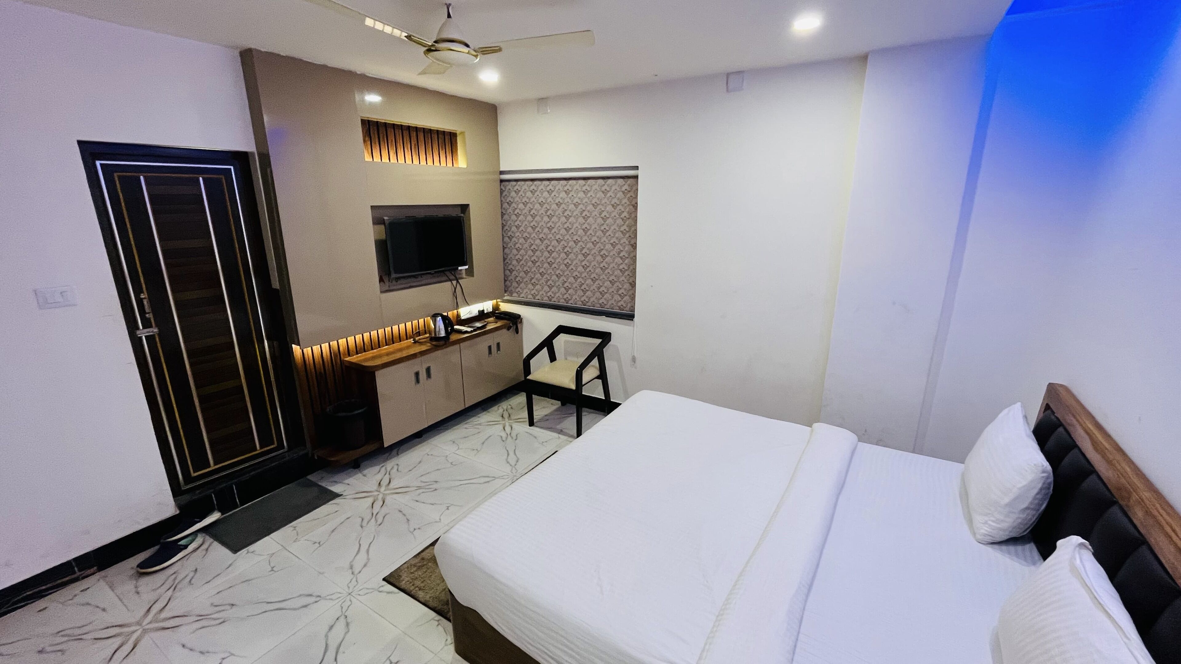 A modern bedroom with a bed, a TV, a desk, and a wardrobe.