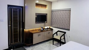 Une chambre d’hôtel équipée d’un lit, d’un bureau avec une chaise, d’une télévision et d’un ventilateur de plafond.
