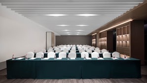 A conference room with rows of white chairs, a long table, and water bottles on the table. - Leeden Hotel Hangzhou (Hangzhou)