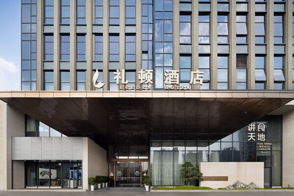 A modern hotel with a large glass facade, a prominent entrance, and signage indicating it is a LEED-certified building. - Leeden Hotel Hangzhou (Hangzhou)