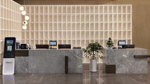 A modern reception desk with multiple computer monitors, a digital kiosk, and a potted plant. - Leeden Hotel Hangzhou (Hangzhou)