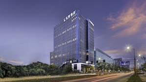 A modern high-rise hotel with a glass facade, multiple floors, and illuminated signage. - Leeden Hotel Hangzhou (Hangzhou)