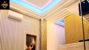 A modern hotel lobby with a wooden reception desk, a staircase, and a wall with vertical lines. - Hotel Shankara Residency (Varanasi)