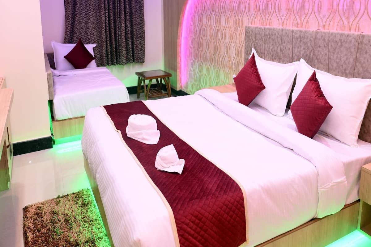 A hotel room with two beds, a small table, and a wall-mounted air conditioner.