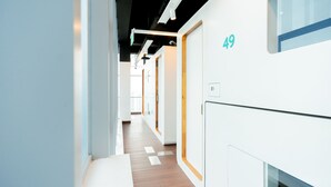 Ein moderner Hotelkorridor mit Holzboden, weißen Wänden und Türen mit der Nummer 49.