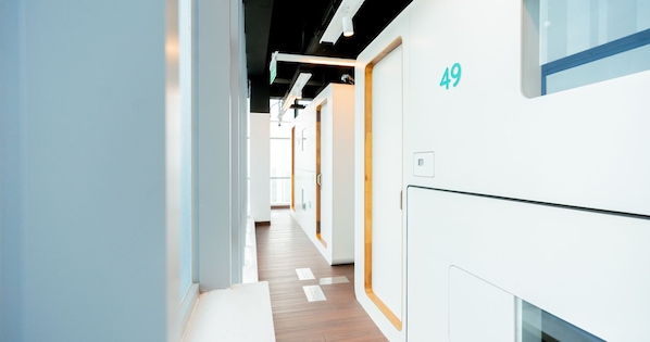 A modern hotel corridor with a wooden floor, white walls, and doors numbered 49.