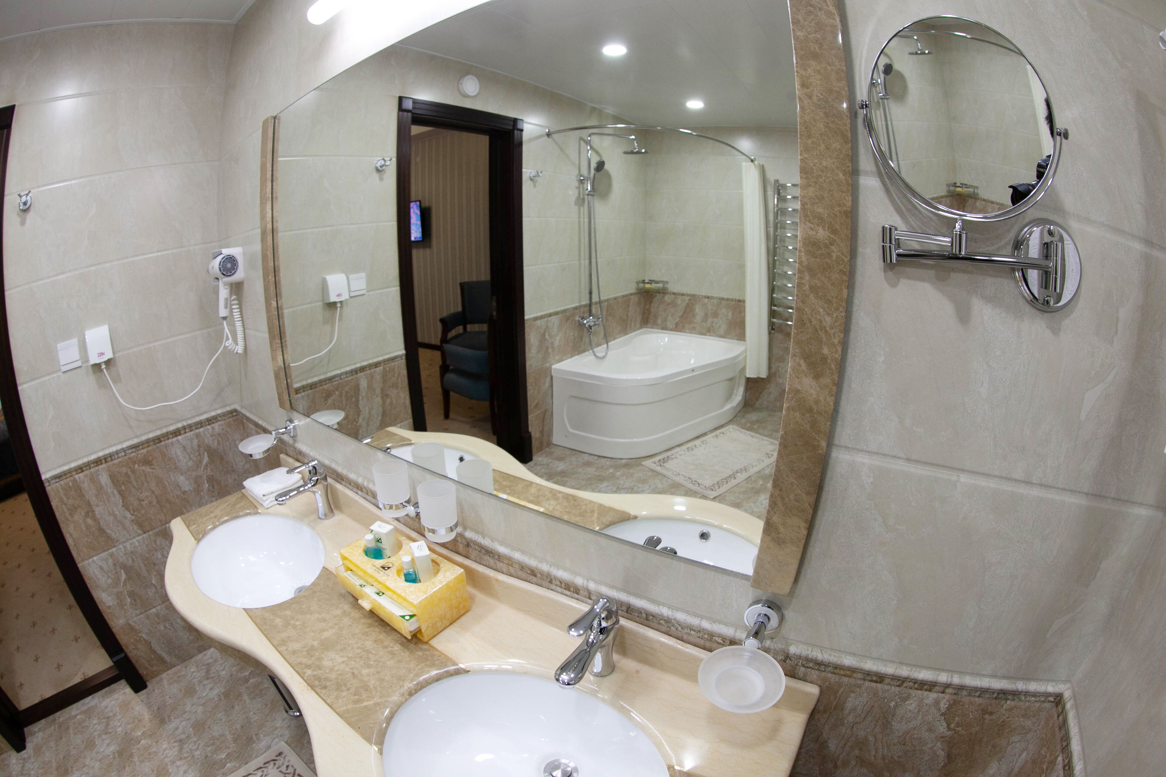 A bathroom with two sinks, a large mirror, and a shower.