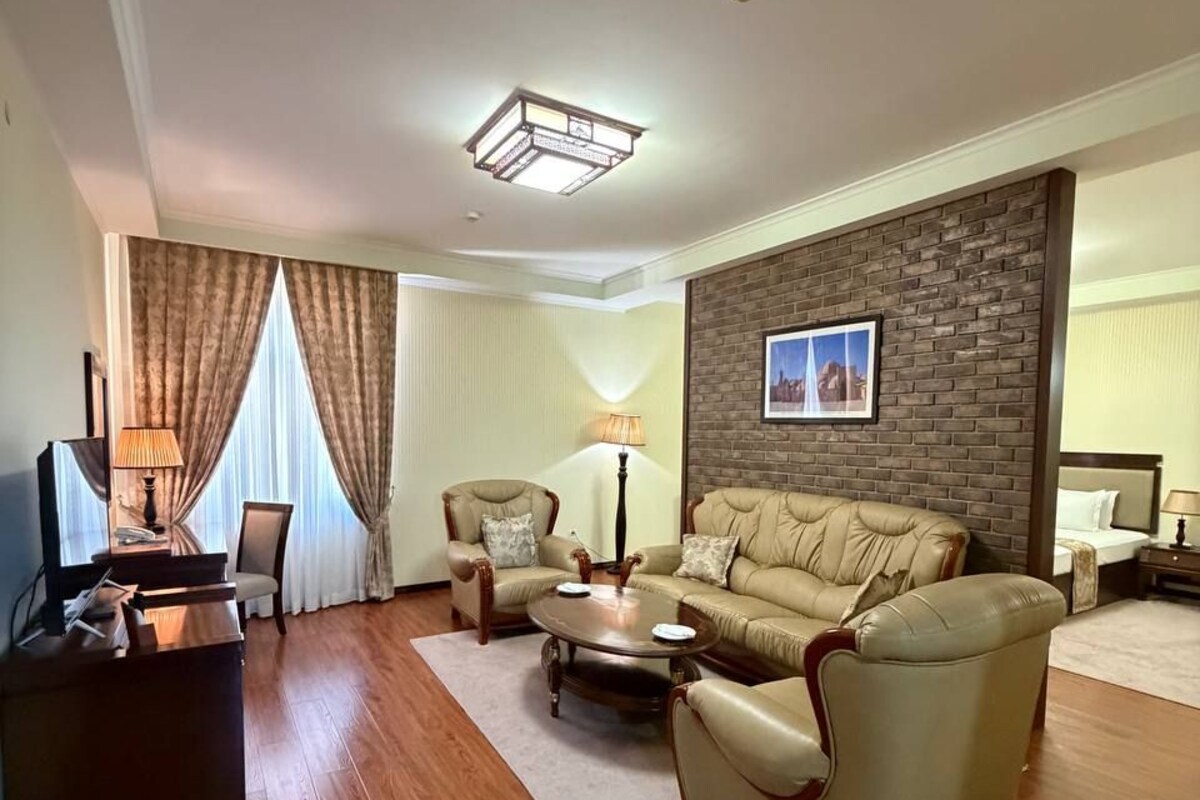 A living room with a sofa, armchairs, a coffee table, a TV, and a fireplace.