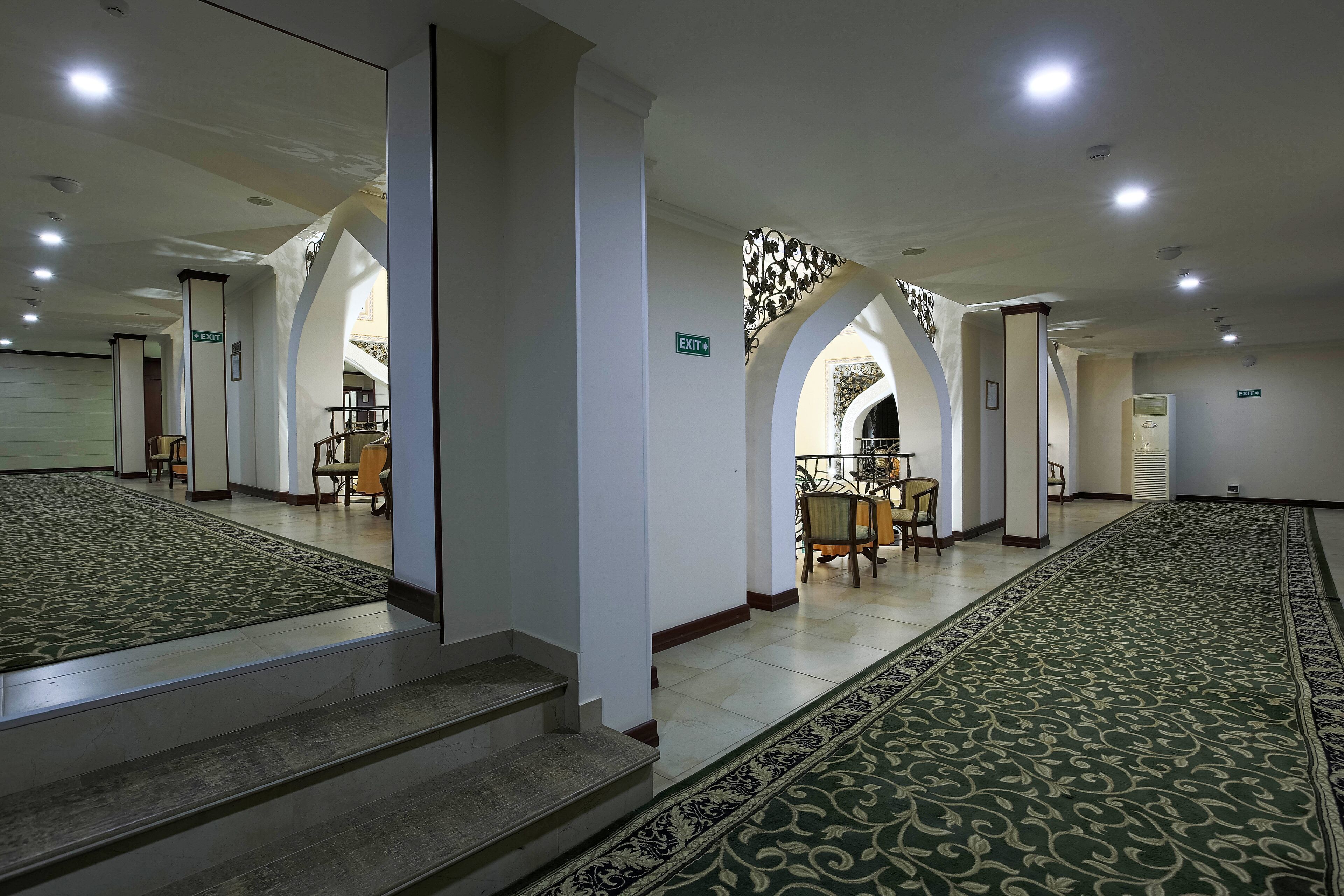 A spacious interior with a central staircase, multiple exits, and a patterned carpet.