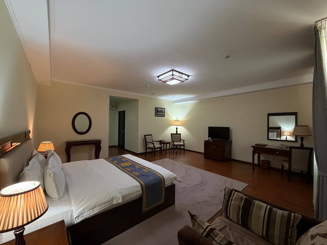 Habitación de hotel con cama, escritorio, televisor y zona de estar.