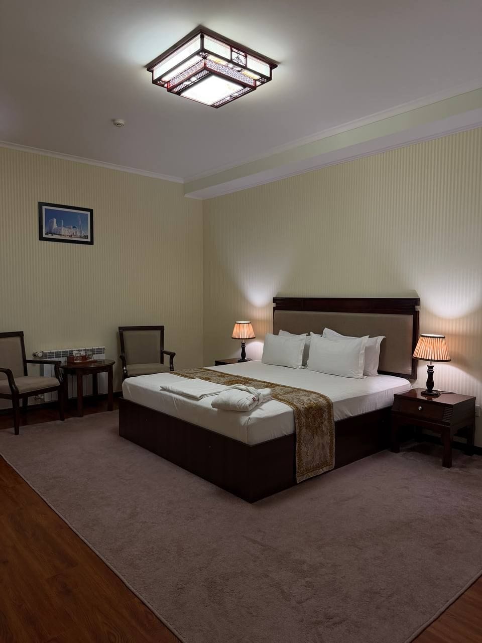 A hotel room with a large bed, two bedside tables, a desk, and a chair.