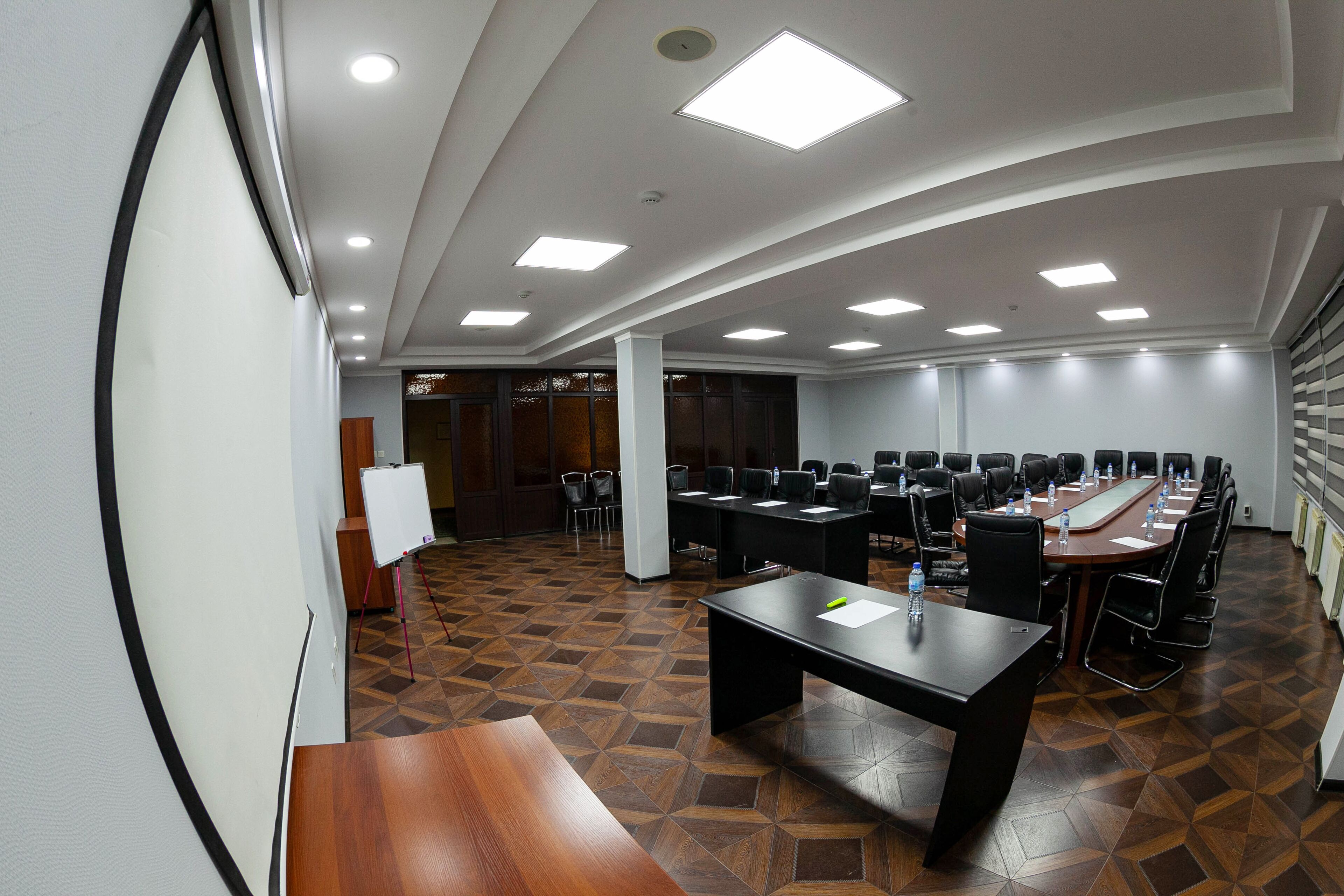 Uma sala de conferências com uma mesa comprida, várias cadeiras e um quadro branco.