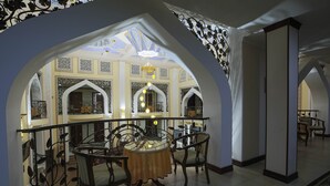 An interior with a balcony, ornate ceiling, and a table with chairs.