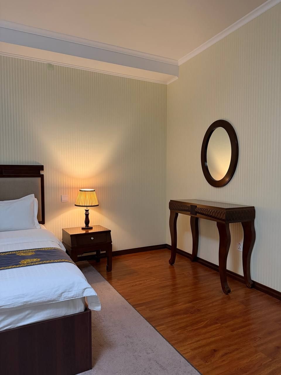 Une chambre d’hôtel avec un lit, une table de chevet, une lampe et un miroir au mur.