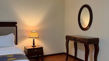 Une chambre d’hôtel avec un lit, une table de chevet, une lampe et un miroir au mur.