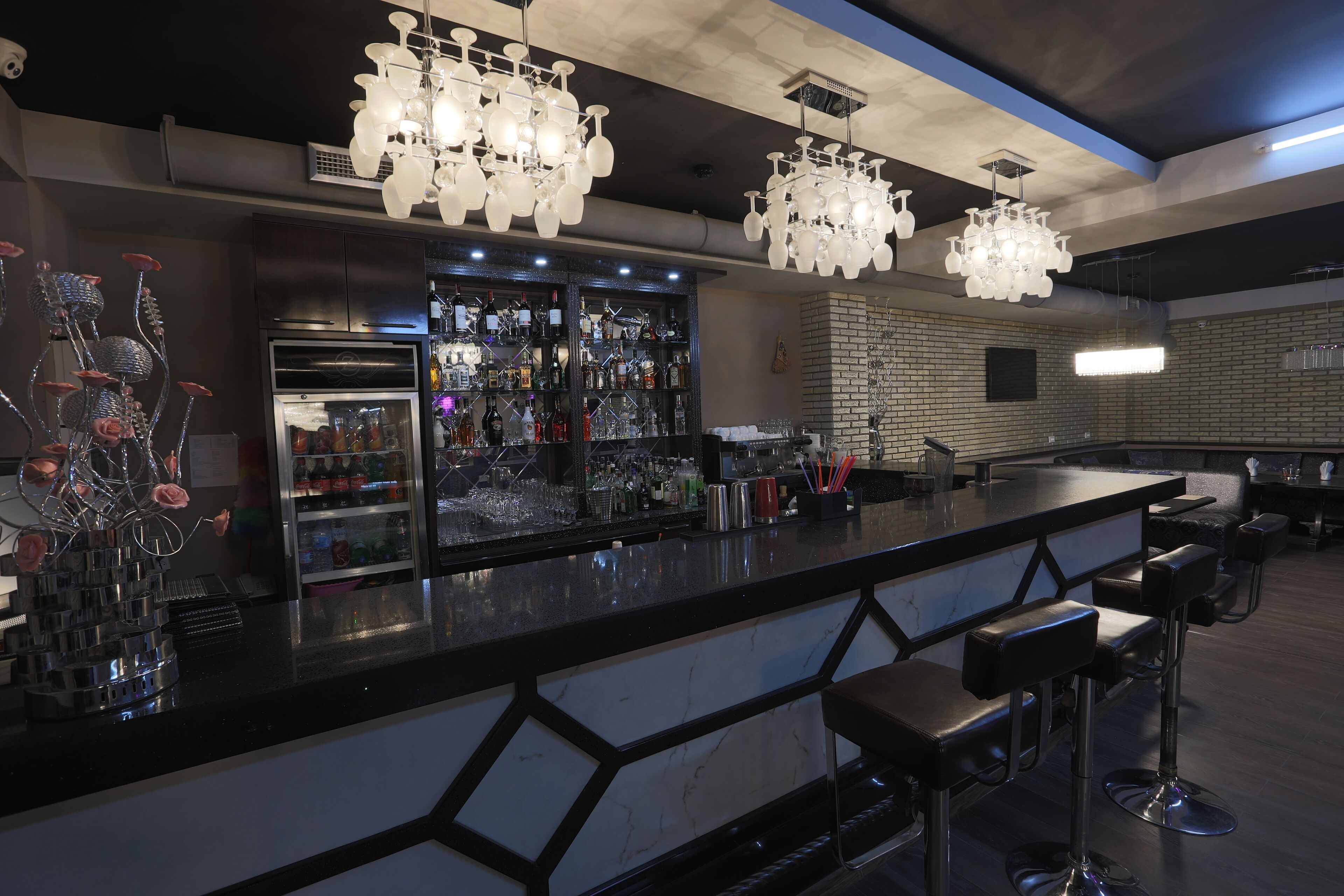 A bar area with a marble countertop, multiple bar stools, and a variety of bottles and glasses.