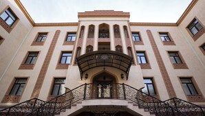 A building with a central entrance, multiple windows, and a decorative balcony.