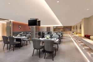 Enjoy communal dining in a spacious, well-lit area with round tables and comfortable seating.
