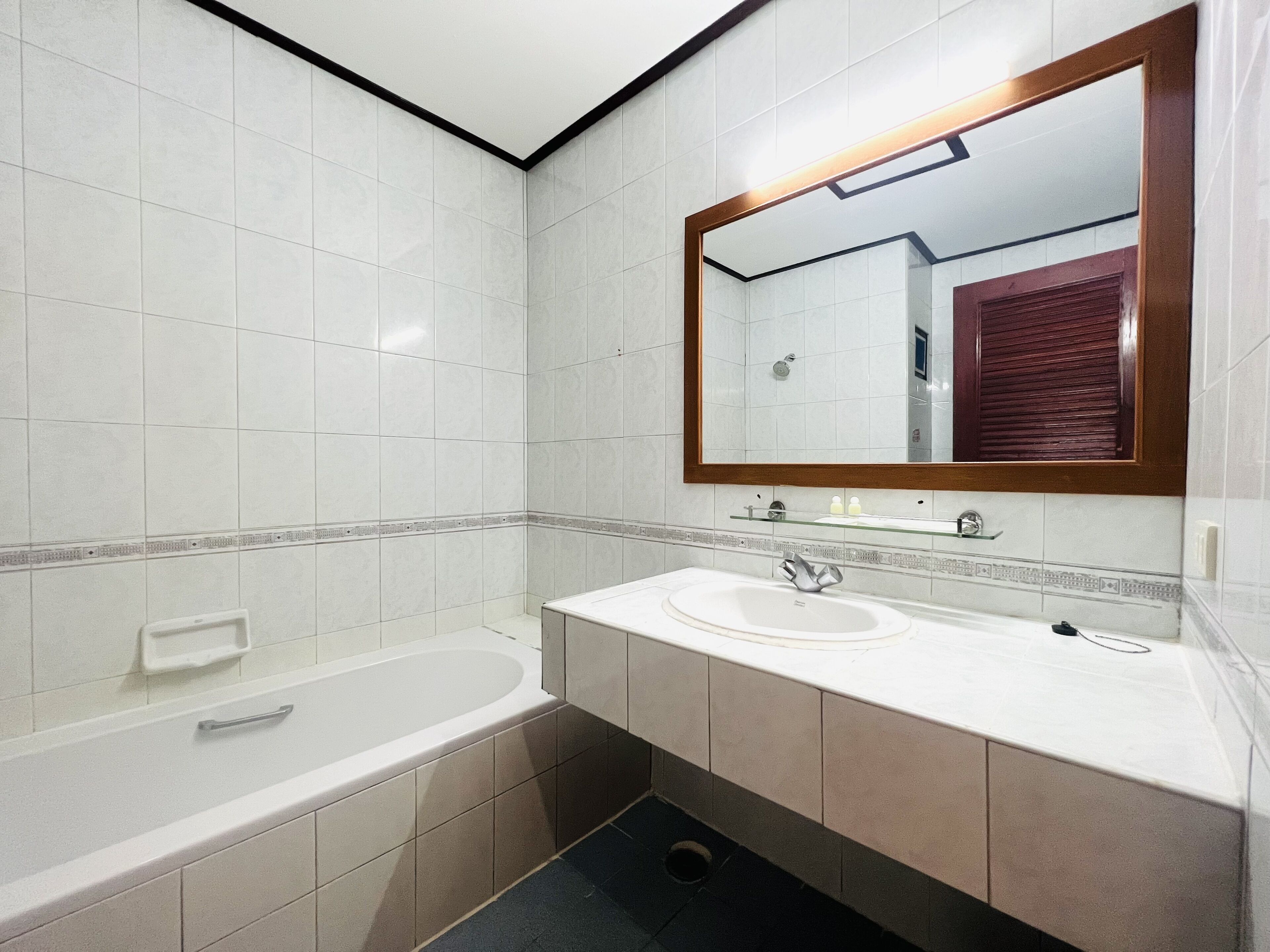 A modern bathroom with a large mirror, two sinks, and a bathtub.