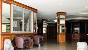 A spacious lobby with a high ceiling, wooden paneling, a large mirror, and a seating area with leather chairs. - PN Mansion (Pattaya)