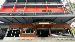 A multi-story building with a prominent red facade, a wooden entrance area, and a sign reading "P.N. MANSION". - PN Mansion (Pattaya)