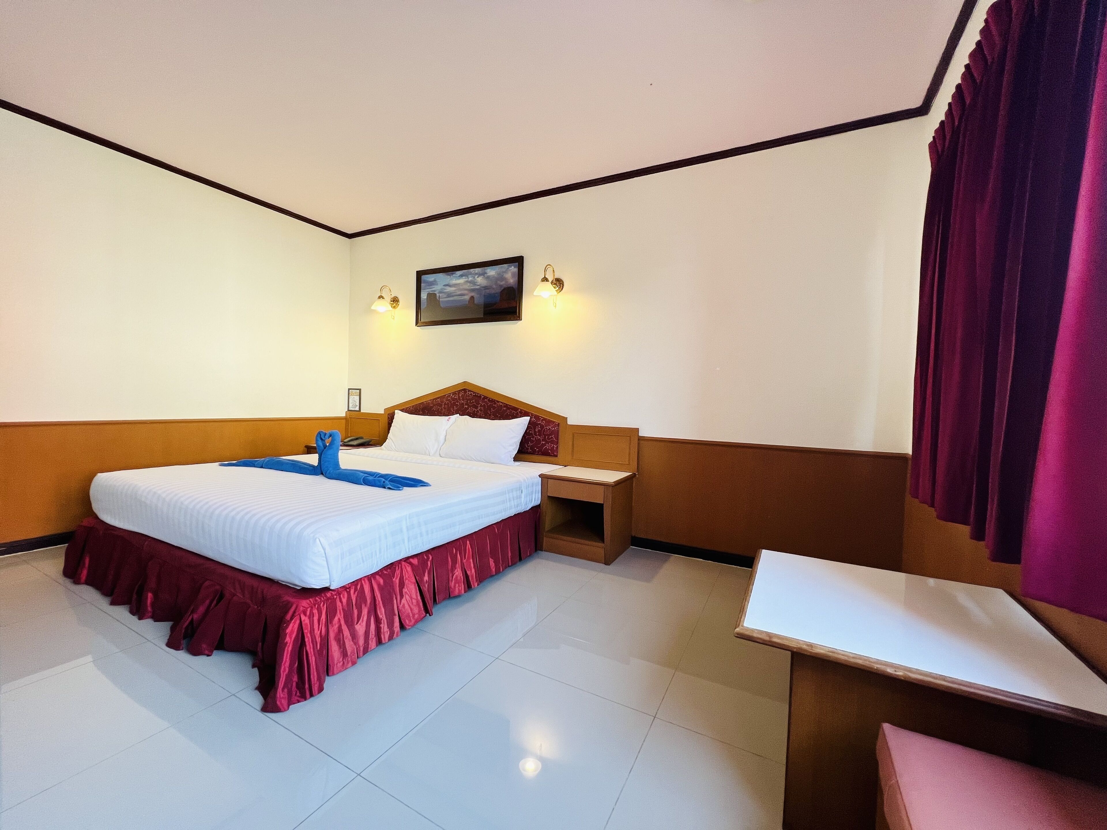 A hotel room with a bed, a desk, and a nightstand.
